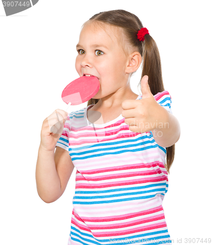 Image of Little girl with lollipop showing thumb up gesture