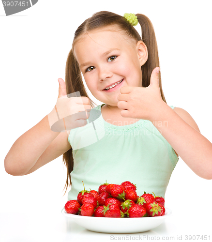 Image of Happy little girl is eating strawberries