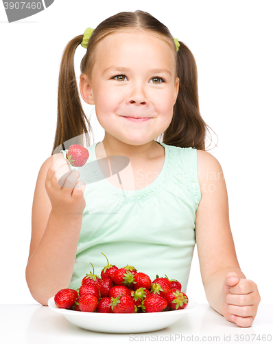 Image of Cheerful little girl is eating strawberries