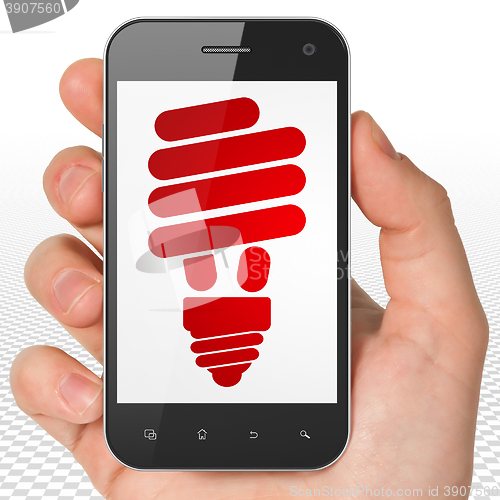 Image of Business concept: Hand Holding Smartphone with Energy Saving Lamp on display