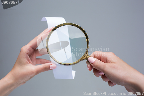 Image of The female hands with  empty transaction paper or paper check and magnifier