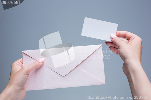 Image of The female hands with envelope against the gray background