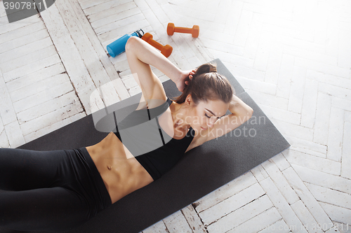 Image of Beautiful slim brunette  doing some stretching exercises in a gym