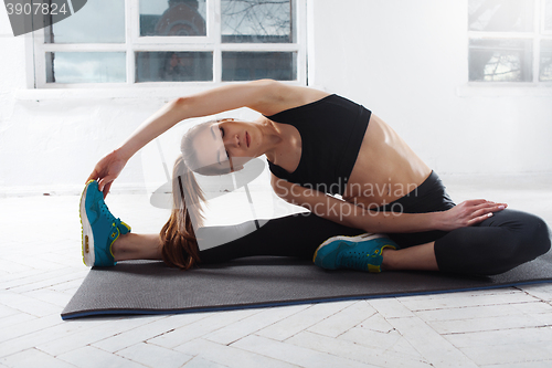 Image of Beautiful slim brunette  doing some stretching exercises in a gym