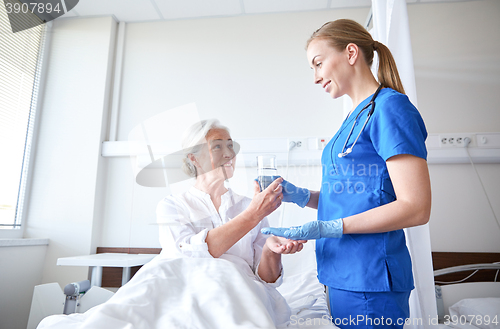 Image of nurse giving medicine to senior woman at hospital