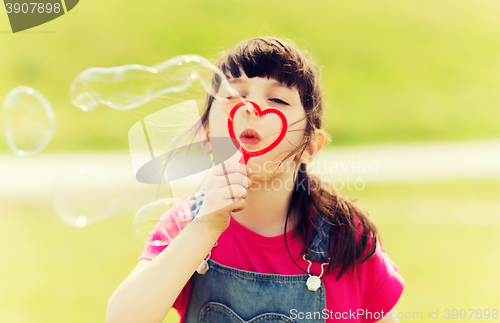 Image of little girl blowing soap bubbles outdoors