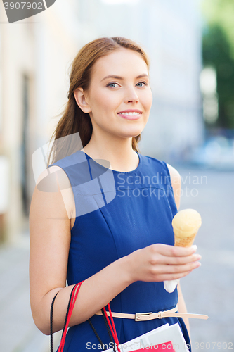 Image of woman with shopping bags and ice cream in city