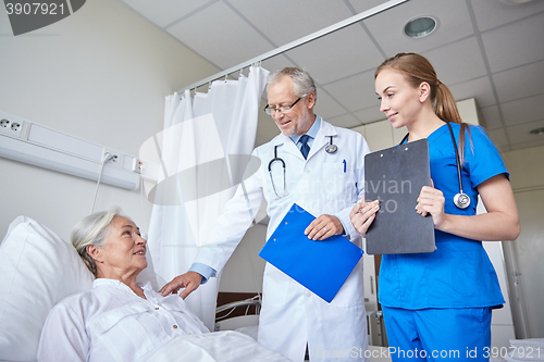 Image of doctor and nurse visiting senior woman at hospital