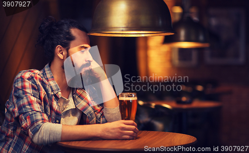 Image of unhappy lonely man drinking beer at bar or pub