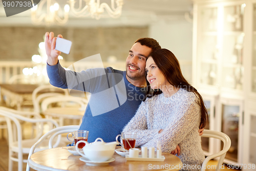 Image of couple taking smartphone selfie at cafe restaurant