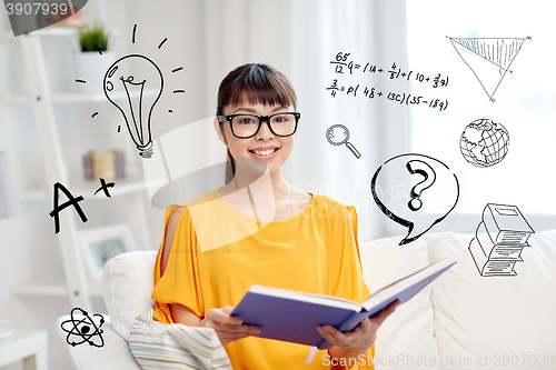 Image of smiling young asian woman reading book at home