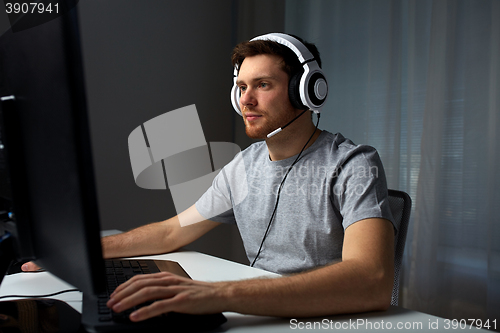 Image of man in headset playing computer video game at home