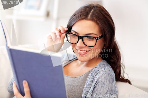 Image of young woman in glasses reading book at home