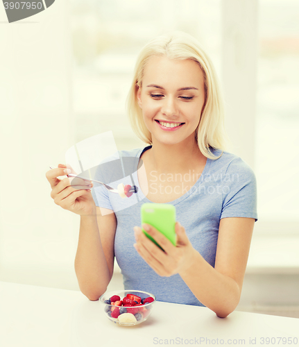 Image of woman with smartphone eating fruits at home