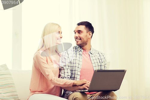 Image of smiling happy couple with laptop computer at home