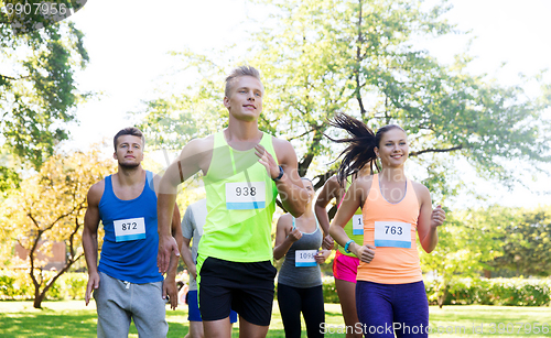 Image of happy young sportsmen racing wit badge numbers