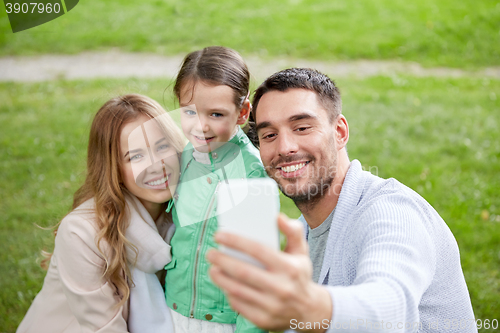 Image of happy family taking selfie by smartphone outdoors