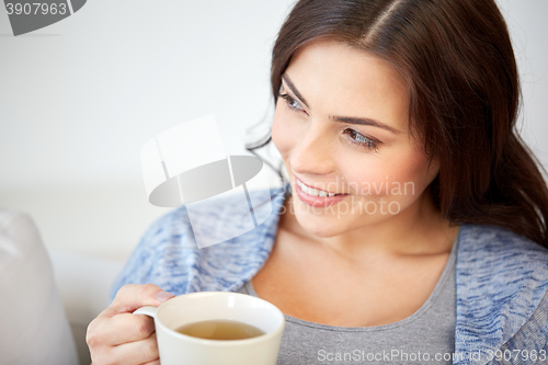 Image of happy woman with cup of tea at home