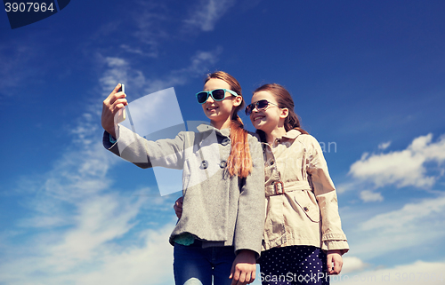Image of happy girls with smartphone taking selfie outdoors