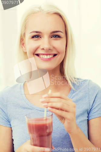 Image of smiling woman drinking juice or shake at home