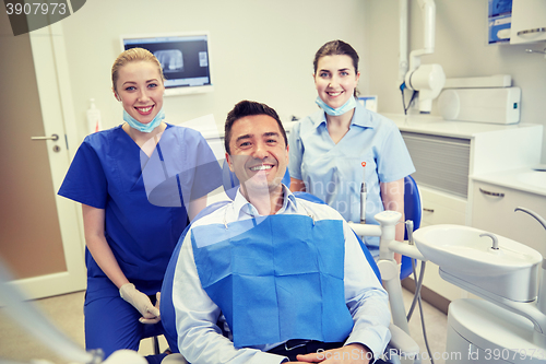 Image of happy female dentists with man patient at clinic