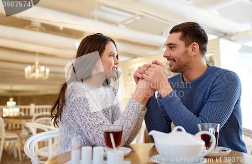 Image of happy couple with tea holding hands at restaurant