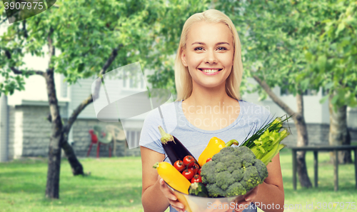 Image of smiling young woman with vegetables in home garden