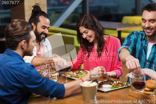 Image of friends eating and tasting food at restaurant