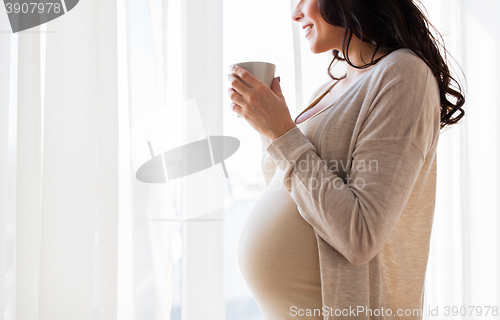 Image of close up of pregnant woman with tea cup at window