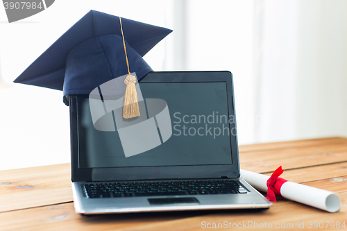 Image of close up of laptop with mortarboard and diploma