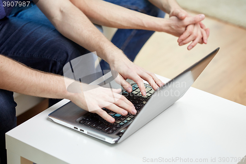 Image of close up of male friends with laptop at home