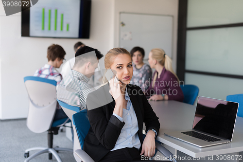 Image of business woman speeking on phone at office with team on meeting 