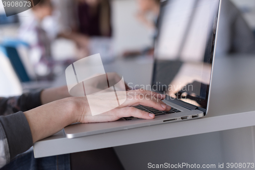 Image of close up of business womans hand typing on laptop with team on m