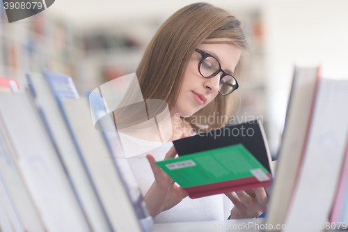 Image of portrait of famale student selecting book to read in library