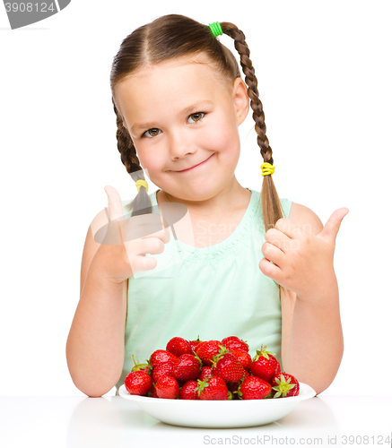 Image of Happy little girl is eating strawberries