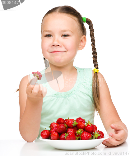 Image of Happy little girl is eating strawberries