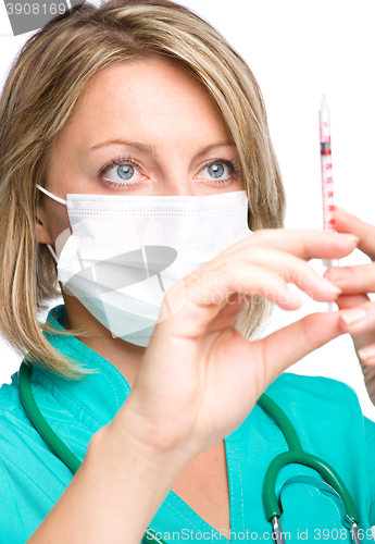 Image of Young nurse is preparing syringe for injection