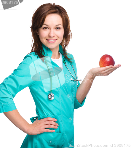 Image of Young lady doctor is holding a red apple