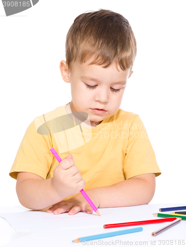 Image of Little boy is drawing using color pencils