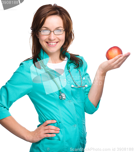 Image of Young lady doctor is holding a red apple