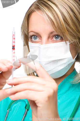 Image of Young nurse is preparing syringe for injection