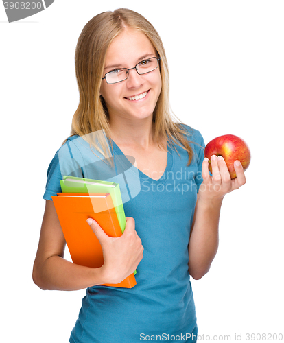 Image of Young student girl is holding book and apple