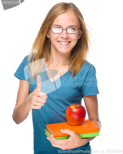 Image of Young student girl is holding book and apple