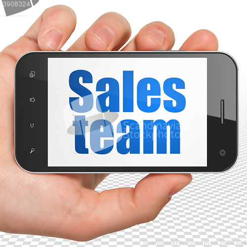 Image of Marketing concept: Hand Holding Smartphone with Sales Team on display