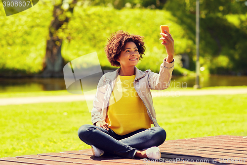 Image of happy african woman taking selfie with smartphone