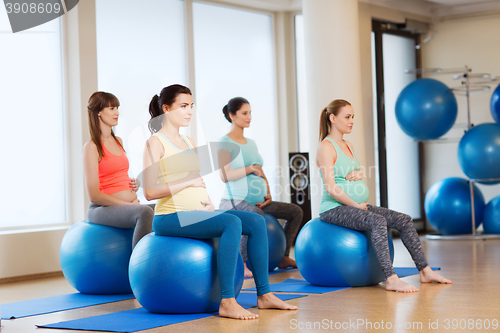 Image of happy pregnant women exercising on fitball in gym