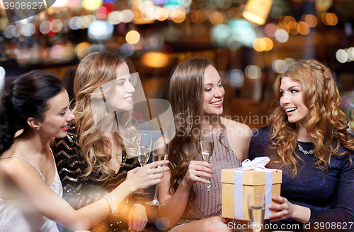 Image of happy women with champagne and gift at night club