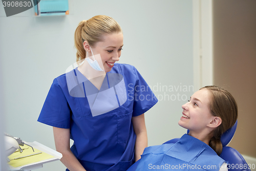 Image of happy female dentist with patient girl at clinic