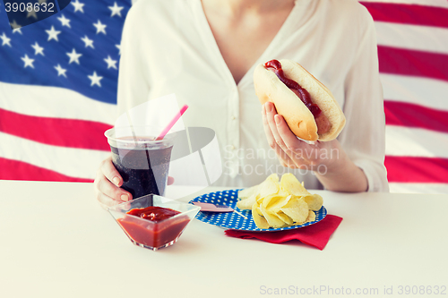 Image of close up of woman eating hot dog with cola