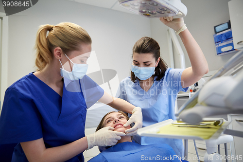 Image of happy female dentist with patient girl at clinic